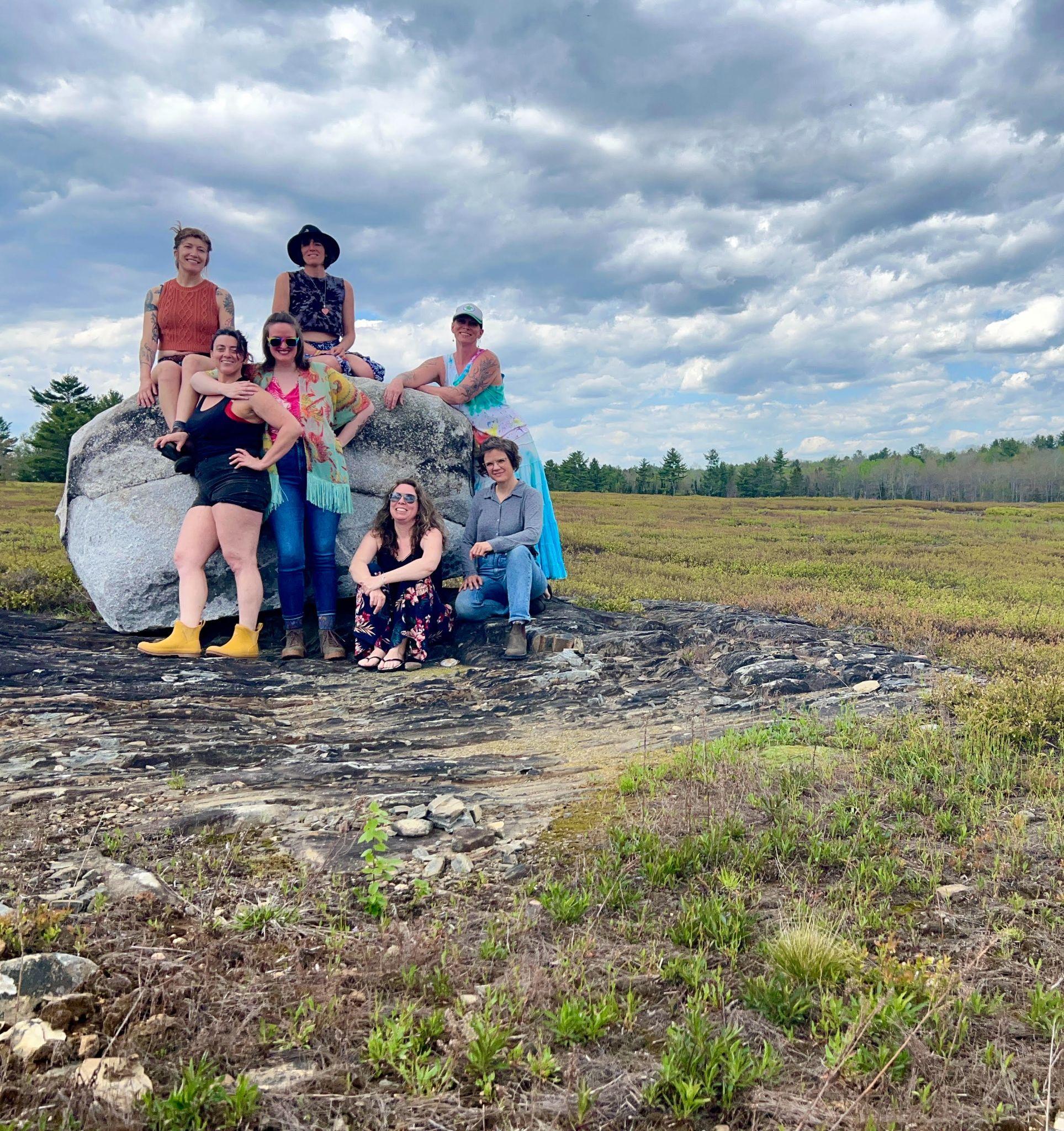Members of the Wild Blueberry Collective gathered on a large boulder in the barrens